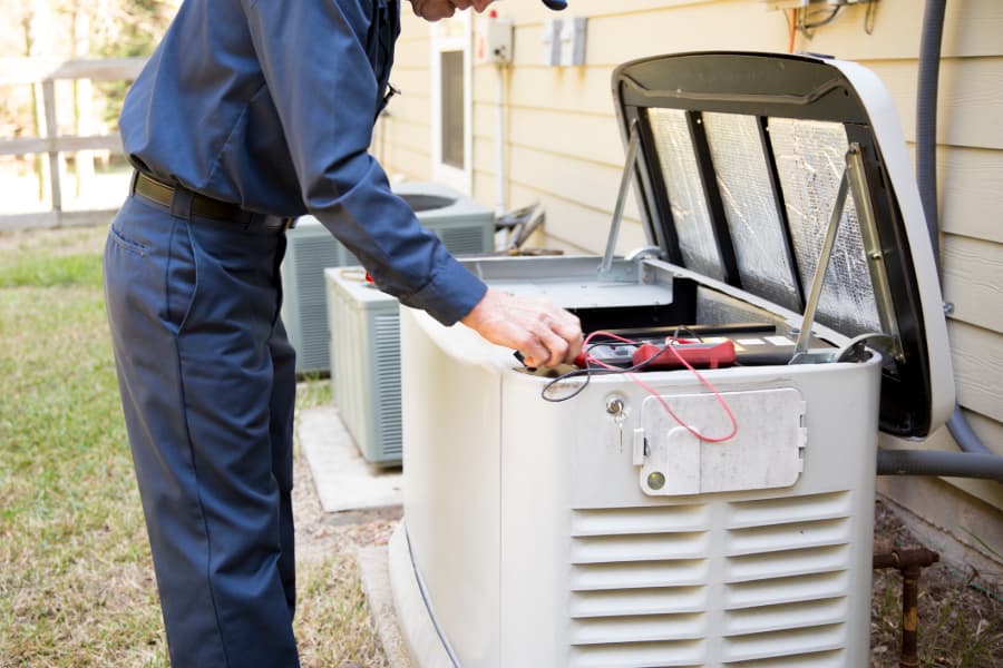 Electrician in blue performing maintenance on generator