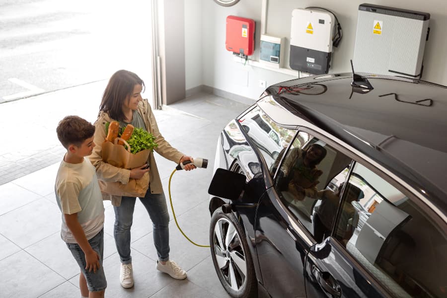 Family charging electric vehicle in their garage