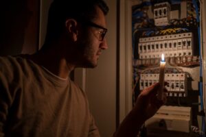 Person in glasses using candle to view circuit breaker